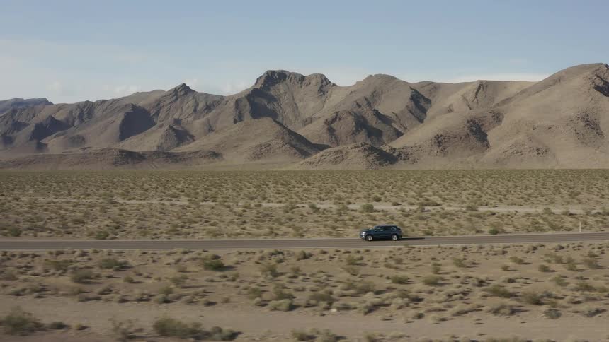 An suv travels on a desert road on a sunny day