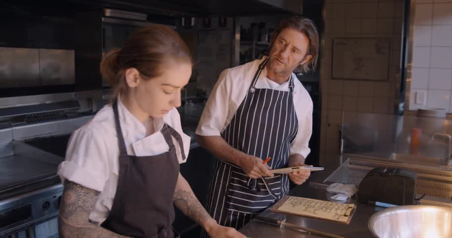 A man and women talk and cook in the restaurant