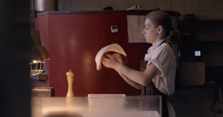 A chef makes pizza dough in a kitchen