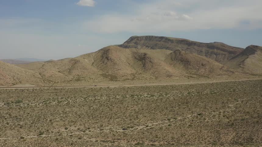 Vehicles travel on a desert road in the distance
