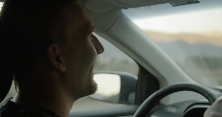 A man smiles and talks as he drives