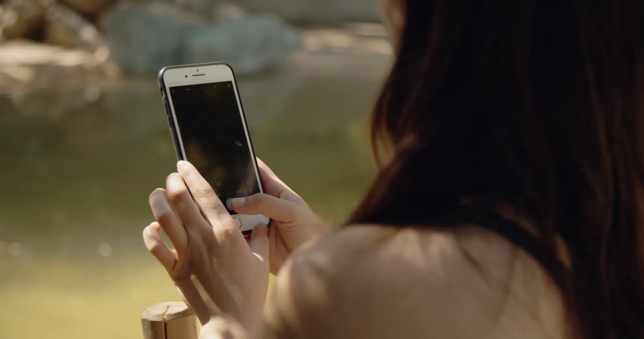 A woman takes a picture of a lake