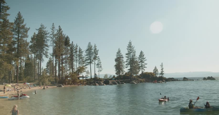 People are in canoes and swimming by the beach