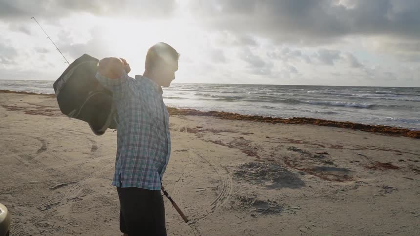 A man fishes on a sandy beach