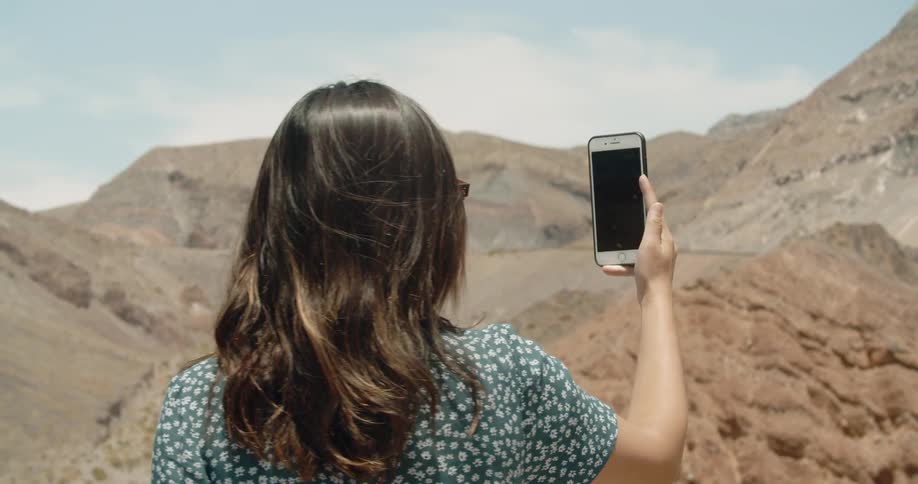 A woman takes a picture in mountains