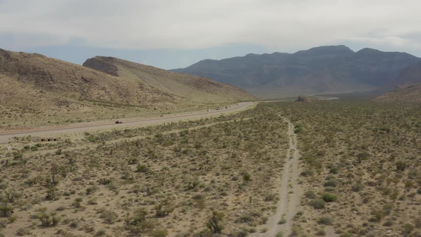 Camera flies toward cars driving along desert highway