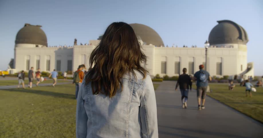 Woman walks on a large yard in front of a temple