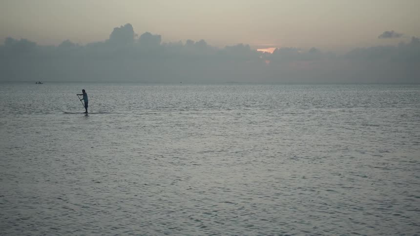 A person is rowing in the water at sunset