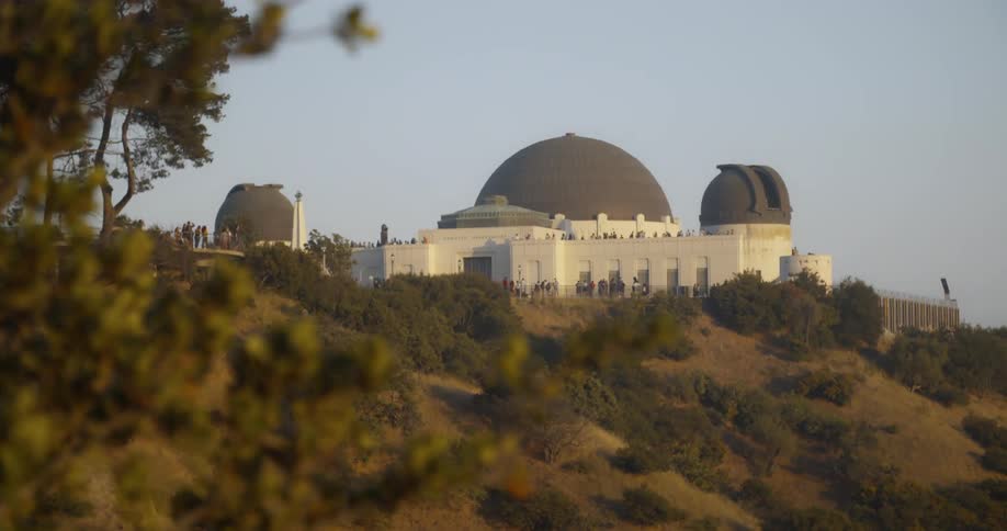 Tourists are standing on a platform at an observatory on a sunny day