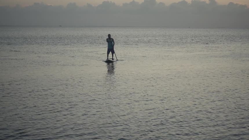 A person rows in the water on a foggy day