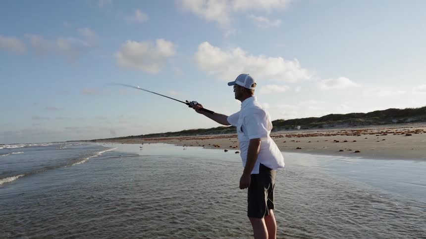 A man fishes on a beach on a windy day