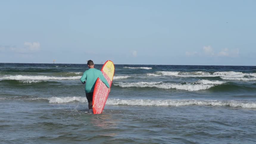 A man carries a surfboard on a beach