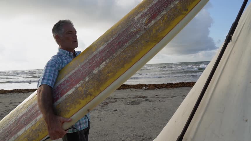 A man holds a surfboard on a beach