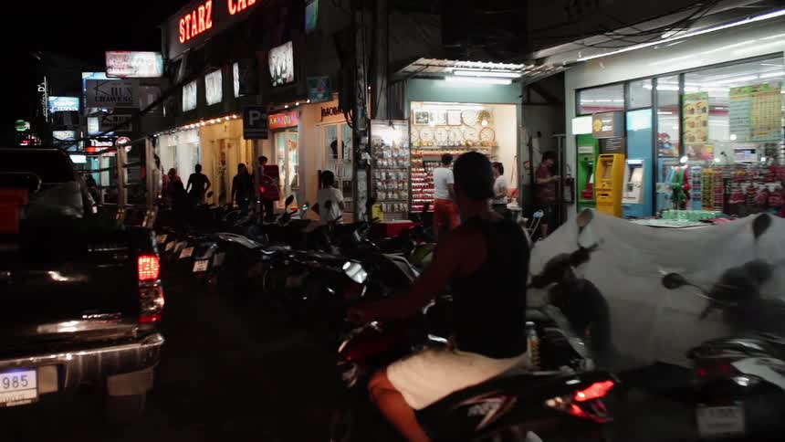 The city street is lined with parked scooters