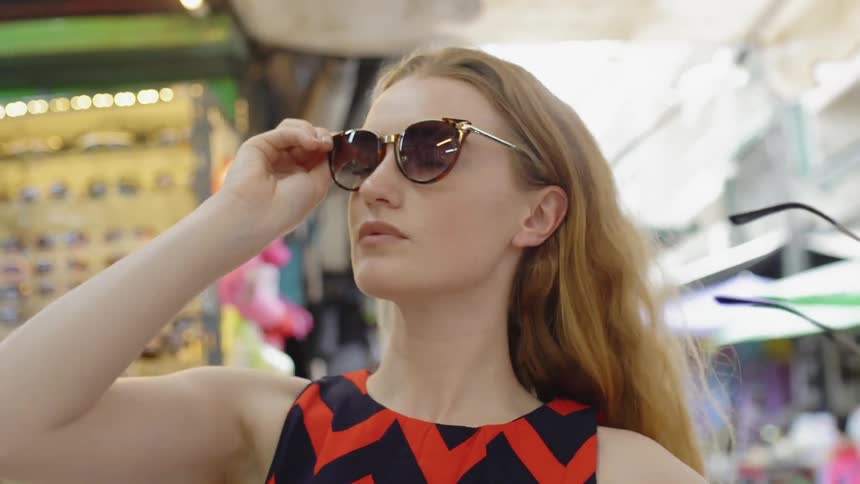 A woman tries on sunglasses in a store