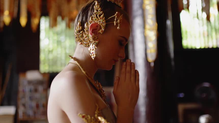Woman wearing bangle earrings clasps her hands in prayer