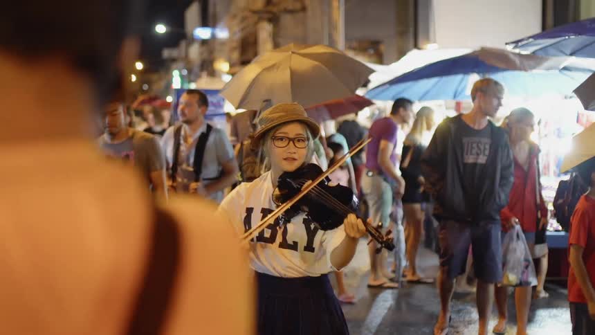 Woman plays the violin in the middle of a crowd