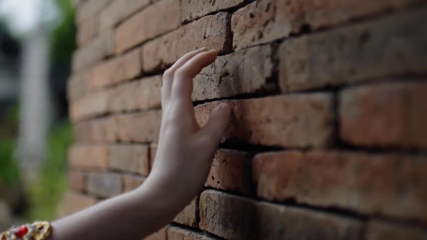 Woman is running her hand on brick building