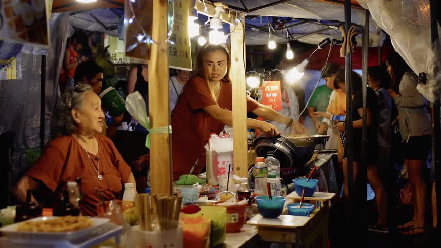 Group of people cook and eat in a large tent