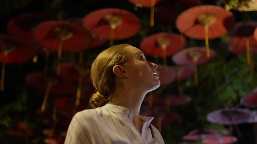 A woman stands beneath parasols hanging from a ceiling