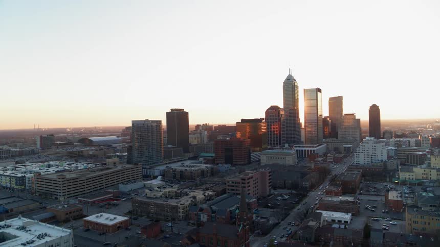 The sun is peeking over skyscrapers as it rises in the morning