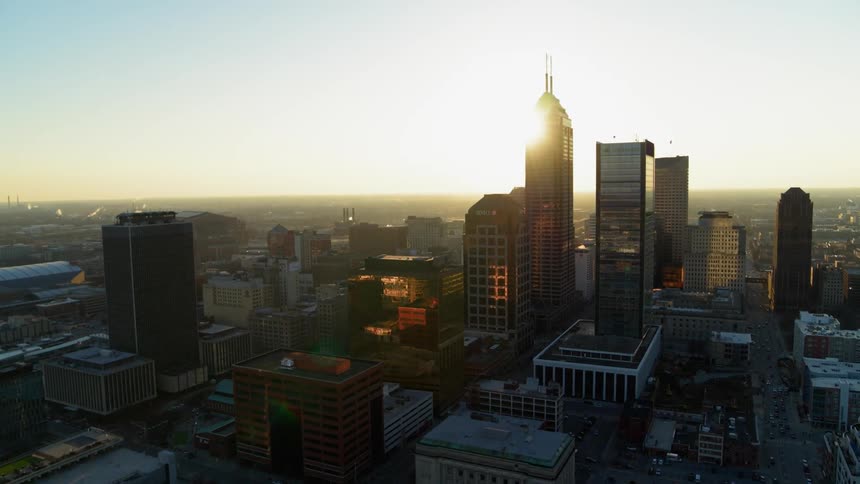 The sun is peeking over skyscrapers as it rises in the morning