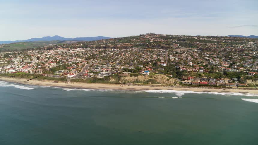 Ocean waves splash to shore next to a city