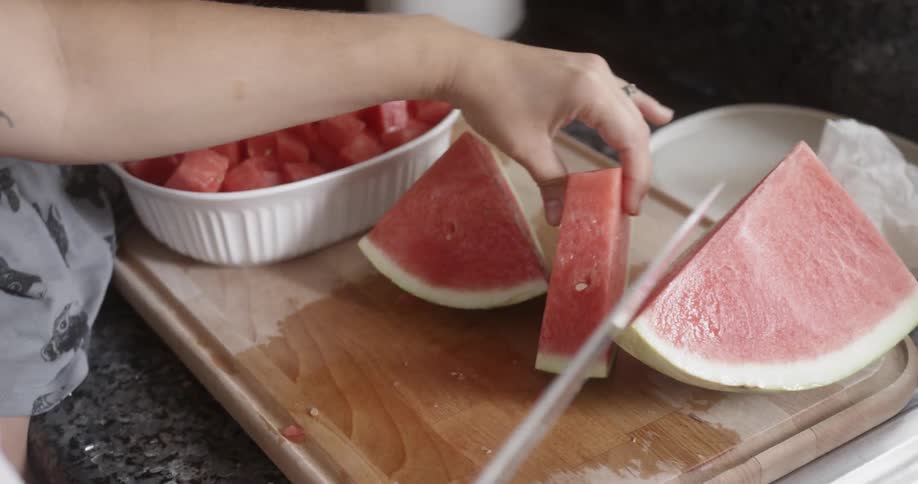 Woman slices a watermelon with a sharp knife