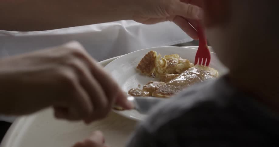 A parent cuts food for a child