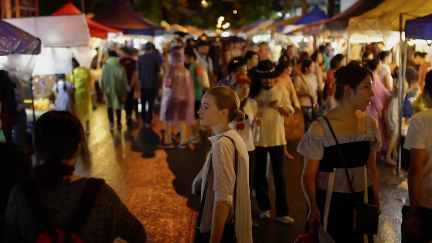 People shop at an outdoor city market at night