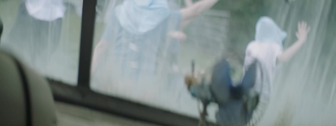 People with hoods over their hands dance around outside