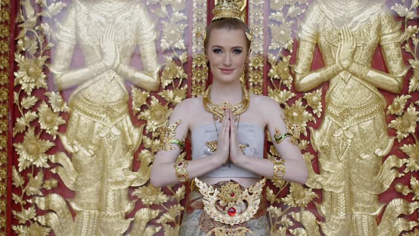 A woman is posing by some gold statues