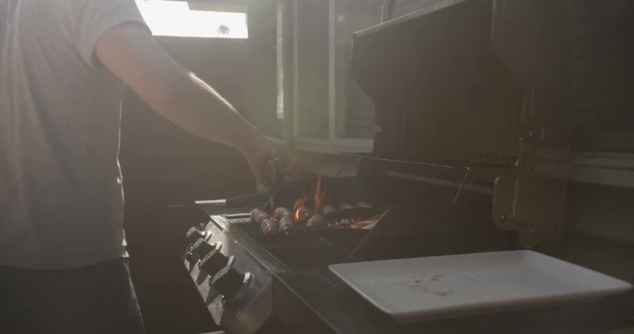 Man turns over food smoking on a grill
