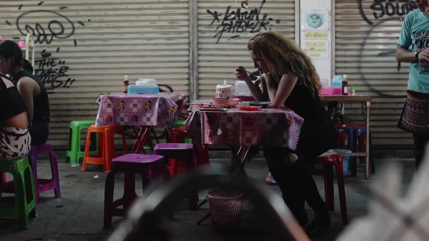 A woman eats noodles at an urban restaurant