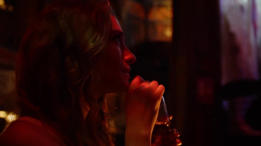 A woman is having a drink and dancing in a club