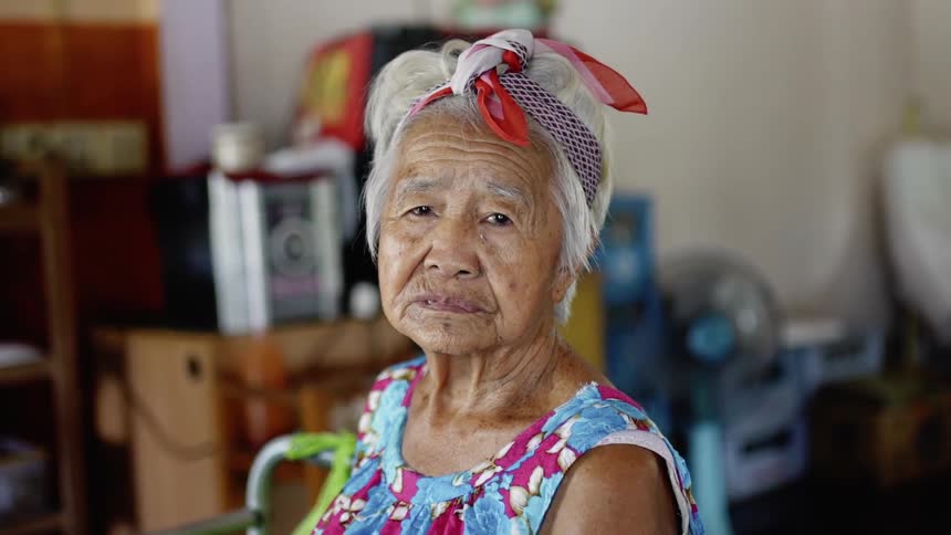 A woman sits staring forward blinking