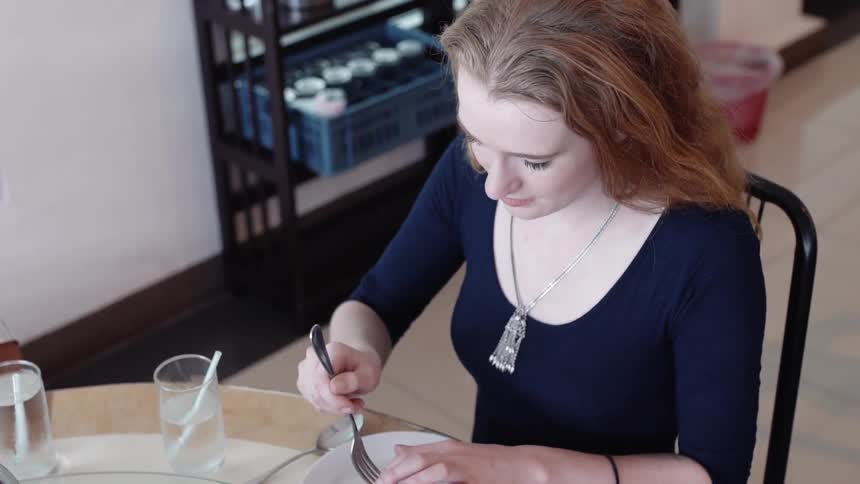 Woman eats at a table in a cafeteria