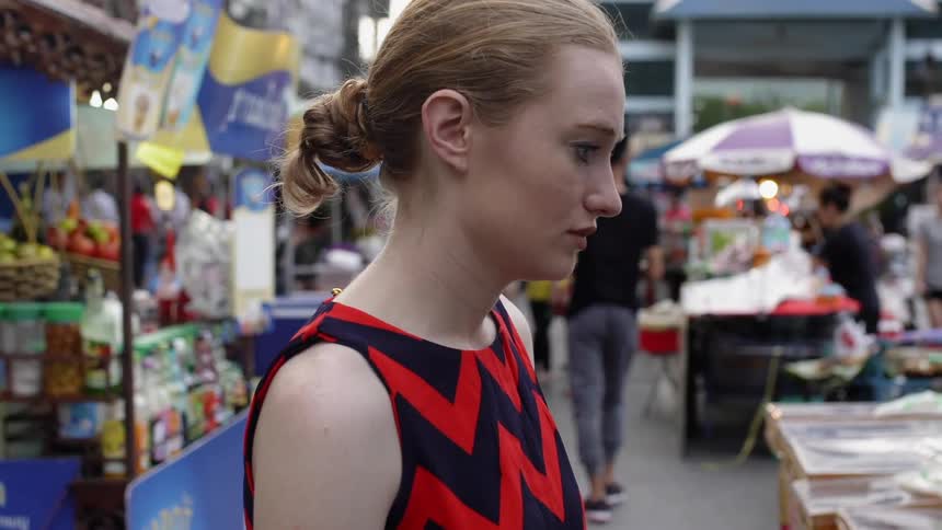 Woman stands looking down at a market stand