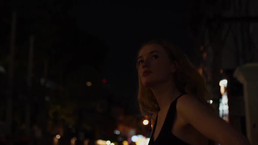 A woman stands outside at night