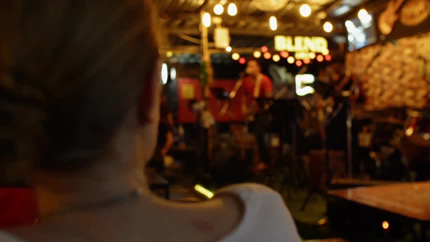 A woman is watching a band on stage
