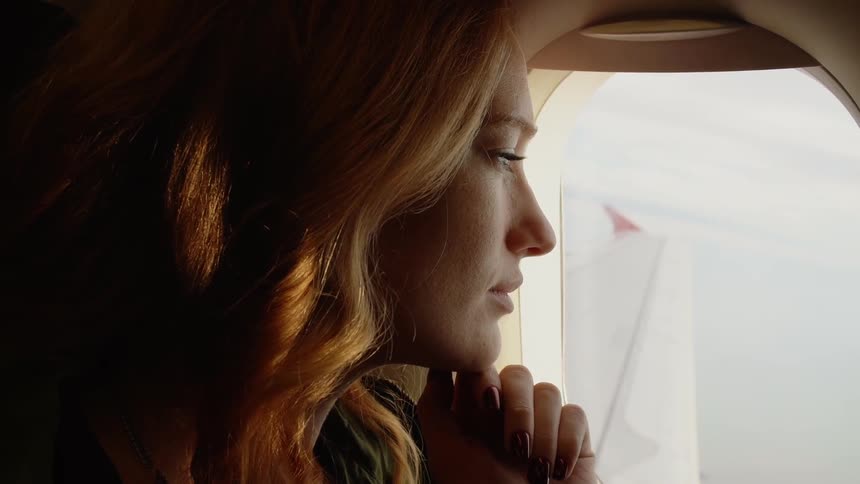 A woman looks out of the plane window