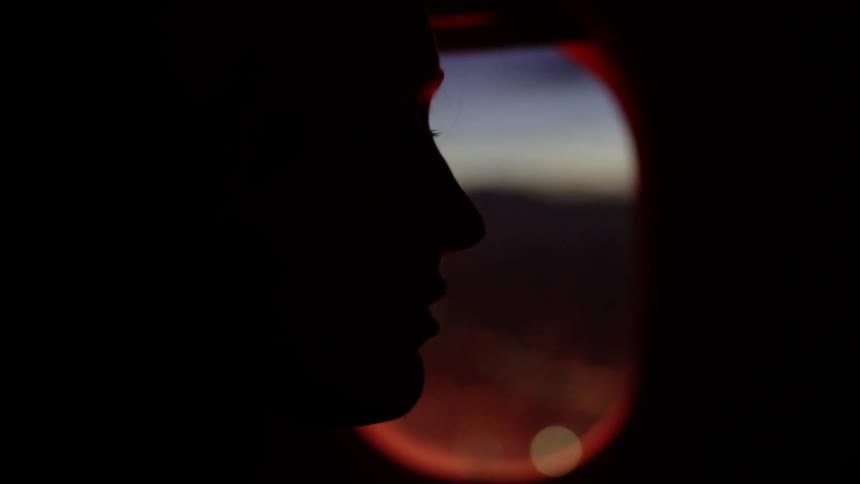 A woman is flying on an airline at dusk