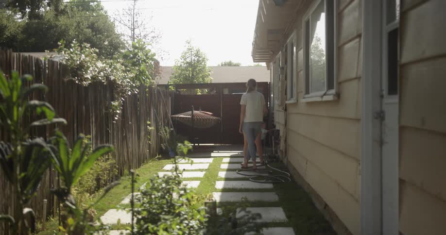 A dog runs in a backyard while two women talk