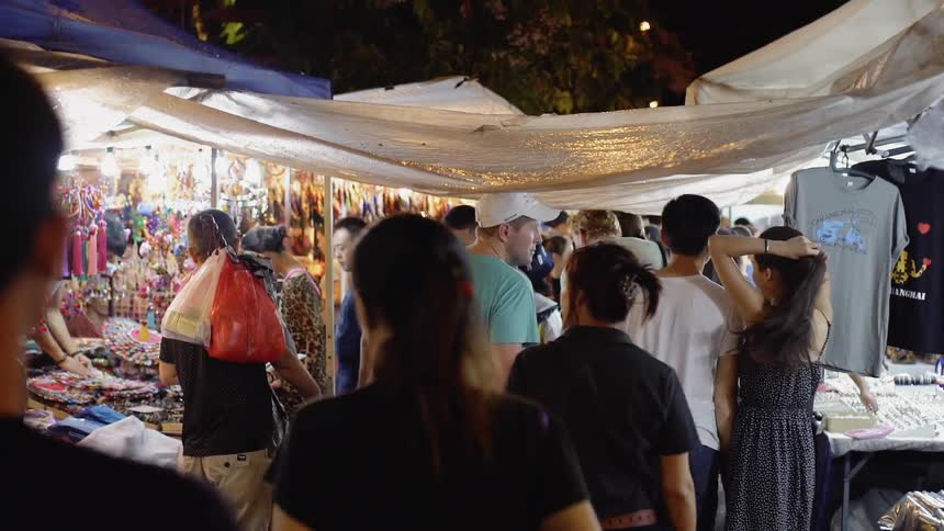 People are wandering through an outdoor market in an asian country at night