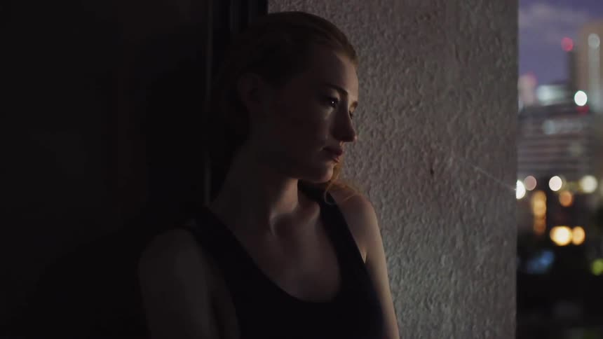 A woman leans against the wall at night