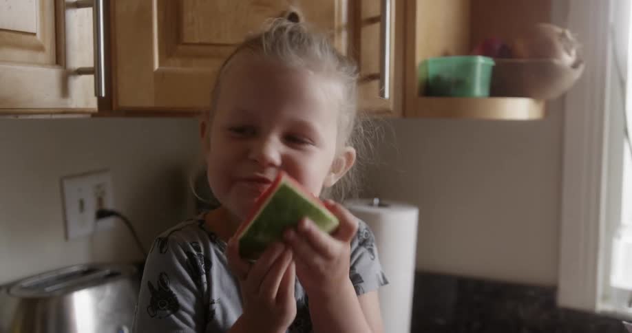 A girl smiles while eating a slice of watermelon