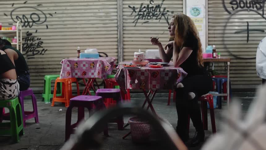 A woman is sitting at a table eating outside