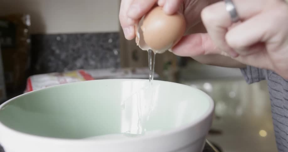 A father helps his young son crack an egg