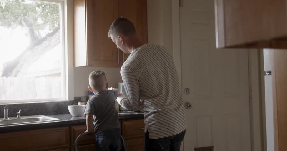 Man and young boy prepare some baking at the kitchen counter