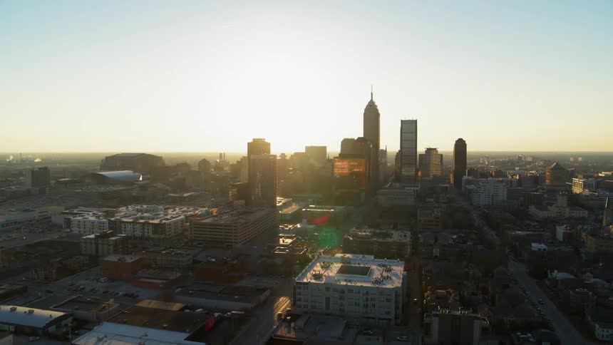 The sun sets behind city skyscrapers